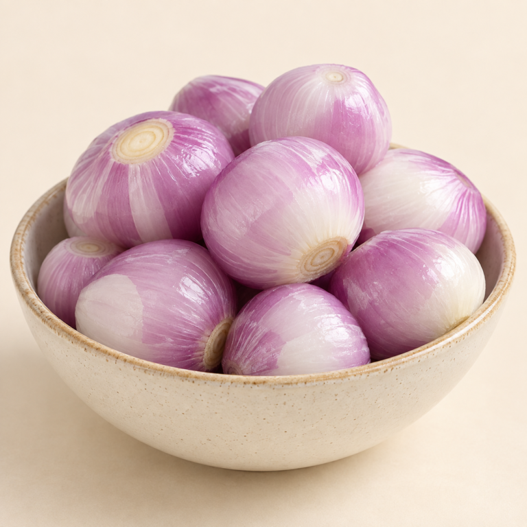 Fresh peeled onions in ceramic bowl showing natural onion color on cream background