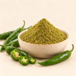 Natural green chilli powder in ceramic bowl with fresh green chillies on cream background